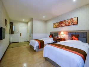 重慶市にあるJUN Hotels Chongqing Nan'an Nanping Dongmoのベッド2台とテレビが備わるホテルルームです。