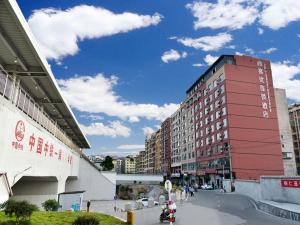 a red building with people riding a motorcycle down a street at Thank Inn Chain Hotel Guizhou Tongren Bijiang District High-speed Railway Station Qingshui Avenue Store in Tongren