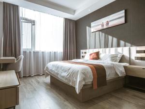 a bedroom with a bed and a large window at JUN Hotels Jiangsu Wuxi East Railway Station Store in Zhaqiao