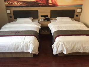 two beds in a hotel room with white sheets at Thank Inn Chain Hotel Jiangsu Nanjing Jiangning Taowu in Nanjing
