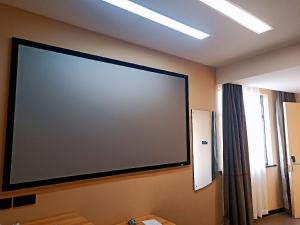 un grand écran de projection sur le mur d'une pièce dans l'établissement Thank Inn Chain Hoteln Jiangsu Suzhou Kunshan Lujia Town Youyi Road, à Suzhou