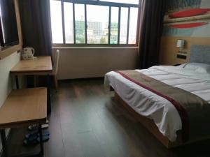 a bedroom with a bed and a desk and a window at Thank Inn Chain Hotel Hebei Hengshui Zaoqiang County Daying Town West Asia Fur Shop in Hengshui