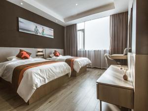 a hotel room with two beds and a tv on the wall at JUN Hotels Jiangsu Wuxi East Railway Station Store in Zhaqiao