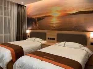 two beds in a hotel room with a painting on the wall at JUN Hotels Hebei Baoding Rongcheng Banzheng North Street Store in Baoding