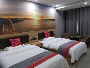 two beds in a hotel room with a painting on the wall at JUN Hotels Suqian Muyang Baimeng Logistics Park in Suqian