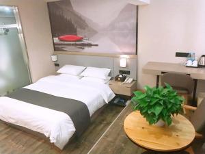 a bedroom with a bed and a desk and a table with a plant at Thank Inn Plus Hotel Jiangsu Suzhou Taicang Liuhe Town Tinghai Road in Taicang