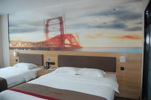 two beds in a hotel room with a painting on the wall at Thank Inn Chain Hotel Weifang High-tech Zone Weifang East Expressway Intersection in Weifang