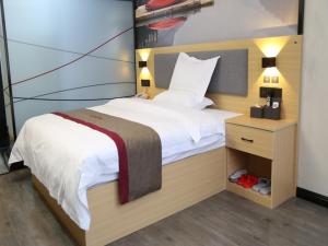 a bedroom with a large bed and a night stand at Thank Inn Chain Hotel Xinyang Gushi County Hongsu Avenue 
