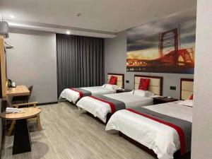 a hotel room with three beds and a painting on the wall at JUN Hotels Suqian Muyang Baimeng Logistics Park in Suqian