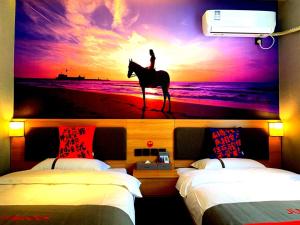 a bedroom with a painting of a person riding a horse on the beach at JUN Hotels Tianjin Jinnan District University City Pingfan Road in Tianjin