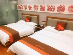 a hotel room with two beds with orange and white sheets at JUN Hotels Jiangsu Taizhou Taixing Zhongnan Central City in Taixing