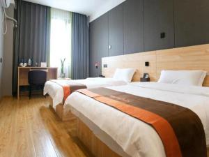 a hotel room with two beds and a desk at JUN Hotels Langfang Guangyang District Wanda Plaza in Langfang