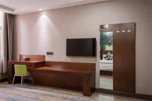 a hotel room with a desk and a flat screen tv at Thank Inn Chain Hotel Shanxi Taiyuan Wanbolin District Wanxiang City in Taiyuan