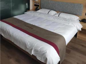 a large bed with white sheets and a brown and white blanket at Thank Inn Chain Hotel Hebei Hengshui Zaoqiang County Daying Town West Asia Fur Shop in Hengshui