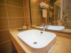 a bathroom with a white sink and a mirror at JUN Hotels Langfang Guangyang District Wanda Plaza in Langfang