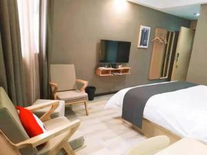 a bedroom with a bed and a tv and a chair at Up and In Hubei Xiaogan Yunmeng County Huguang Road 