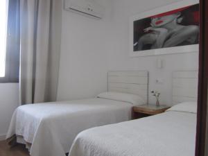 una habitación con 2 camas y una pintura de una mujer en Hospedaje Villanueva, en Tarifa