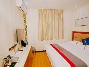 a hotel room with a bed and a desk with a computer at JUN Hotels Gansu Jiayuguan Jingtie District Guanghui Community in Jiayuguan