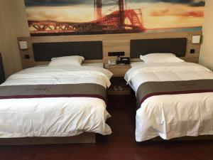 two beds in a room with a painting on the wall at Thank Inn Chain Hotel Jiangsu Nanjing Jiangning Taowu in Nanjing