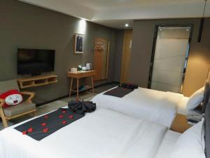 a bedroom with two beds and a flat screen tv at Up and In Hubei Xiaogan Yunmeng County Huguang Road 