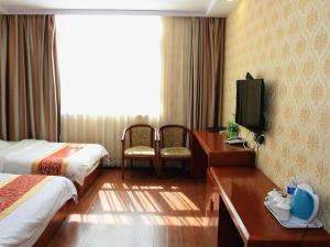 Habitación de hotel con 2 camas, escritorio y TV. en JUN Hotels Zhangjiakou Qiaodong District Yu'er Mountain Taihe Home, en Zhangjiakou