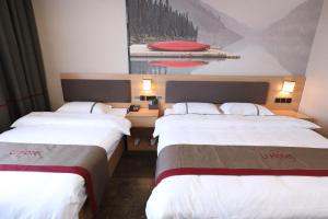 two beds in a hotel room with a picture on the wall at Thank Inn Plus Hotel Qingdao Jiaozhou Jiaoping Road high-speed intersection in Qingdao
