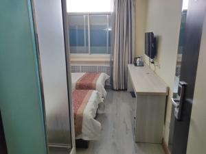 a room with two beds and a desk and a window at JUN Hotels Yulin Yuyang District Xinlou Store in Yulin