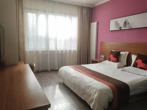 um quarto com uma cama grande e uma parede rosa em JUN Hotels Gansu Lanzhou Chengguan DIstrict Lanzhou University em Lanzhou