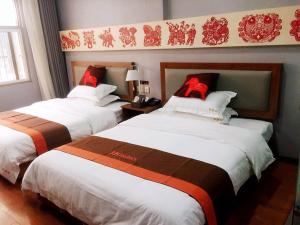 two beds in a hotel room with red bows on them at JUN Hotels Jiangsu Taizhou Taixing Zhongnan Central City in Taixing