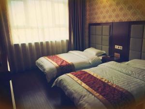 um quarto de hotel com duas camas e uma janela em JUN Hotels Zhangjiakou Qiaodong District Yu'er Mountain Taihe Home em Zhangjiakou
