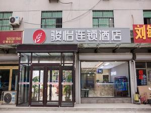un magasin avec un panneau sur le côté d'un bâtiment dans l'établissement JUN Hotels Shandong Heze Development Zone Shanghai Road, à Xinji
