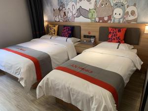 a hotel room with two beds and a mural at JUN Hotels Tianjin Jinnan District University City Pingfan Road in Tianjin