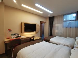 a hotel room with two beds and a desk and a television at Thank Inn Chain Hotel Yunnan Dali Yunlong County Caojian Town Wanghuan Road in Caojian
