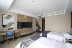 a bedroom with two beds and a desk and a television at Up And In Anhui Huainan Tianjiaan District Hualian Commercial Building in Huainan