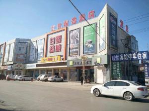 um carro branco estacionado em frente a um edifício em JUN Hotels Hebei Hengshui Shenzhou Bus Station em Hengshui