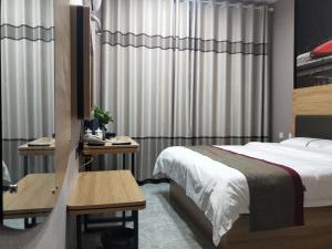 um quarto de hotel com uma cama, uma secretária e cortinas em Thank Inn Chain Hotel Shandong Linyi Linshu County Cangshan South Road em Linyi