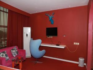 a living room with a red wall with a blue chair at JUN Hotels Jiangnan Nanchang Nanchang County Xiaolan Industrial Park in Nanchang