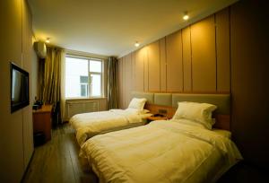 太原市にあるJUN Hotels Shanxi Taiyuan Gaoxin Communityのベッド2台とテレビが備わるホテルルームです。