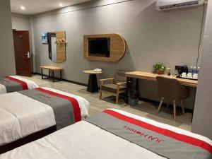 a hotel room with two beds and a desk and a tv at JUN Hotels Suqian Muyang Baimeng Logistics Park in Suqian
