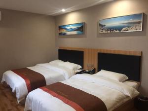 two beds in a hotel room with two at JUN Hotels Henan Luoyang Xigong District Central Bus Station in Luoyang