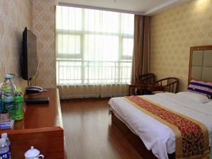 um quarto de hotel com uma cama, uma secretária e uma janela em JUN Hotels Zhangjiakou Qiaodong District Yu'er Mountain Taihe Home em Zhangjiakou