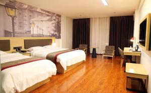 a hotel room with two beds and a desk at Thank Inn Chain Hotel Guangdong Heyuan Yuancheng District Heyuan Avenue North White Bailingtou Gaotang Store in Heyuan
