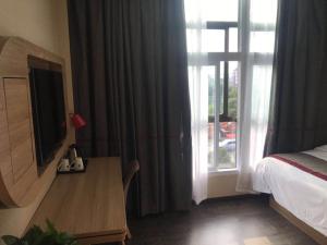 a bedroom with a bed and a tv and a window at Thank Inn Chain Hotel Jiangsu Nanjing Jiangning Taowu in Nanjing