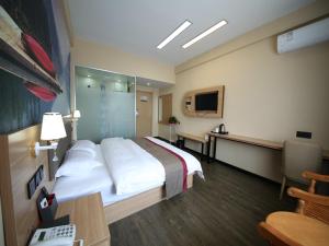 a hotel room with a large bed and a desk at Thank Inn Chain Hotel Shandong Dezhou Lingcheng District Lingzhou Road Ginza in Dezhou
