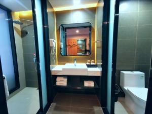 a bathroom with a sink and a mirror and a toilet at Thank Inn Plus Hotel Jining Qufu Confucius Museum in Jining