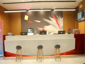 a lobby with a counter with stools in front at Thank Inn Chain Hotel Xinyang Gushi County Hongsu Avenue 