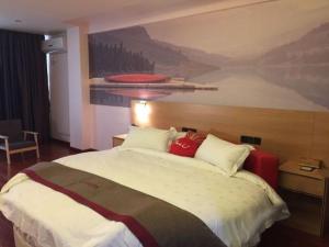 a bedroom with a large bed with a painting on the wall at Thank Inn Chain Hotel Guangdong Heyuan Yuancheng District Heyuan Avenue North White Bailingtou Gaotang Store in Heyuan