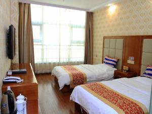 a hotel room with two beds and a television at JUN Hotels Zhangjiakou Qiaodong District Yu'er Mountain Taihe Home in Zhangjiakou