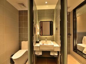 a bathroom with a sink and a toilet and a mirror at Lano Hotel Guangdong Heyuan Dongyuan County Administrative Avenue in Heyuan