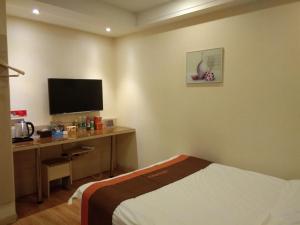 a hotel room with a bed and a desk with a television at JUN Hotels Anhui Suzhou Lingbi County Riyue Star City Laidi Shopping Street Store in Suzhou